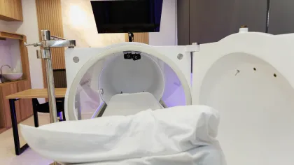 Modern white hyperbaric oxygen therapy chamber in a clean clinical room with wooden and gray walls.