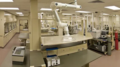 Spacious modern laboratory with advanced fume extraction arms and various scientific equipment on workbenches.