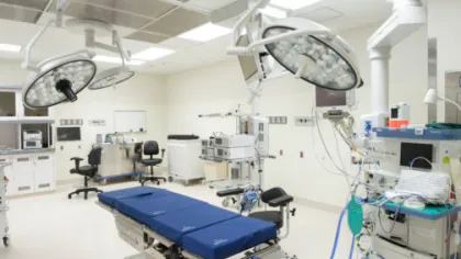 Modern hospital operating room with surgical lights, operating table, monitors, and medical equipment.