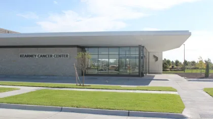 Modern Kearney Cancer Center building with large glass windows and well-maintained surrounding lawn under blue sky