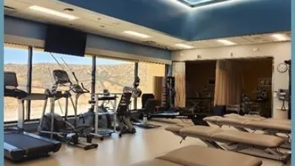 Modern rehabilitation gym with treatment tables, cardio equipment, and a galaxy-themed ceiling light panel.