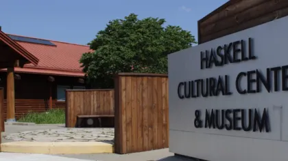 Entrance to Haskell Cultural Center and Museum with wooden structures and clear blue sky background.