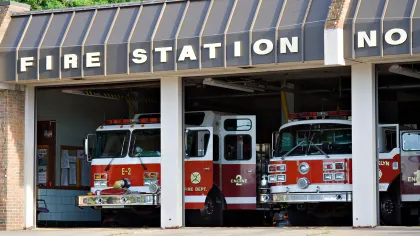 Red and white fire trucks parked inside a brick fire station with a sign reading Fire Station No.