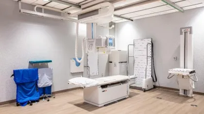 Modern X-ray imaging room with examination table, protective aprons, and advanced radiology equipment.