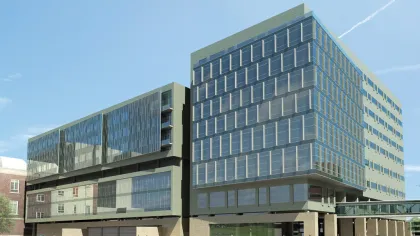 Modern glass and concrete office building with reflective windows under a blue sky on a sunny day.
