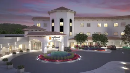 Dignity Health St. John's Pleasant Valley hospital building exterior at dusk with lit windows and landscaped circular driveway.