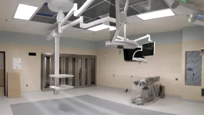 Empty modern operating room with ceiling-mounted monitors, equipment, and overhead surgical lights.