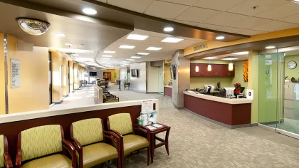 Bright and spacious dental clinic waiting area with green chairs, reception desk, and modern lighting.
