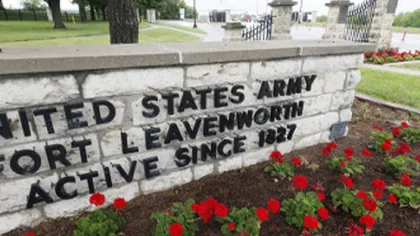 Stone sign reading United States Army Fort Leavenworth active since 1827 with red flowers in foreground