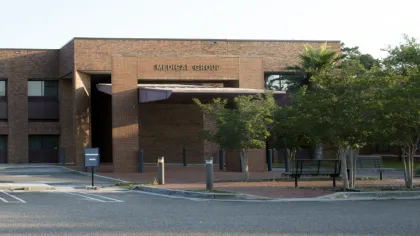 Exterior view of a brick medical group building with a parking lot and trees in front during daytime