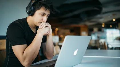 a person wearing headphones and sitting at a table with a laptop