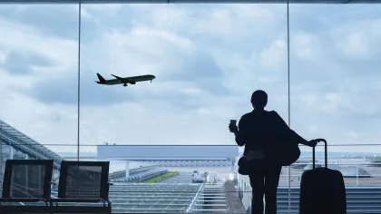 a person taking a picture of an airplane flying over a runway