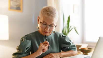 a person sitting at a table with a laptop and a pen