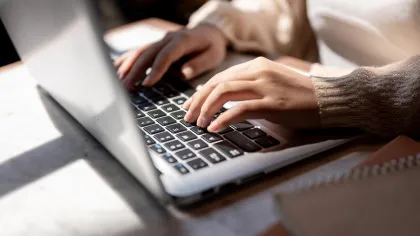 a close-up of hands typing on a laptop