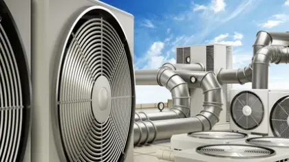 Industrial air conditioning units and ventilation pipes installed on a rooftop under a blue sky with clouds