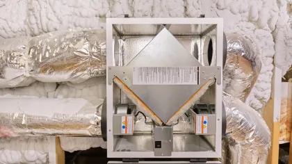 Open HVAC heat recovery ventilator unit with insulated ductwork in a mechanical room.