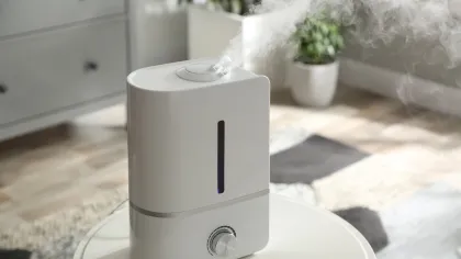 White humidifier releasing mist in a bright, modern living room setting on a round table.