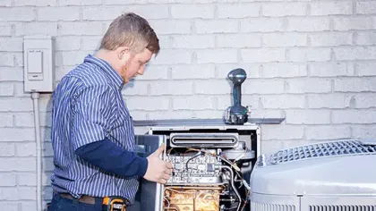 Technician inspecting and repairing an outdoor HVAC unit against a white brick wall background.