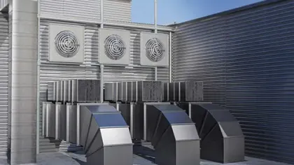 Commercial HVAC system with ventilation ducts and industrial fans installed outside a building under a clear sky