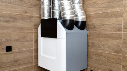 Modern HVAC unit with insulated ventilation ducts mounted on wood-paneled wall for indoor climate control.