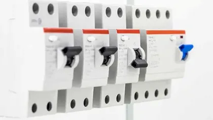 Close-up of multiple circuit breaker switches with black and blue toggles on a white panel.