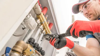 a man in a red hat and gloves working on a machine