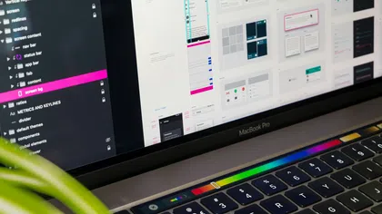 MacBook Pro displaying UI design software with colorful touch bar and layered interface elements.