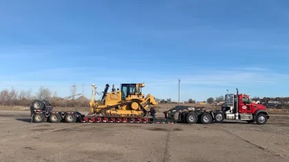 a tractor pulling a trailer with Cadillac Ranch in the background