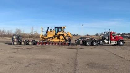 a tractor pulling a trailer with Cadillac Ranch in the background