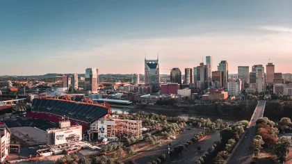 Aerial view of Nissan Stadium and downtown Nashville skyline under a clear sky during sunset.