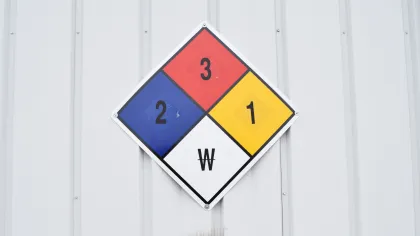 NFPA hazard diamond sign on a metal wall showing red 3, blue 2, yellow 1, and white W ratings