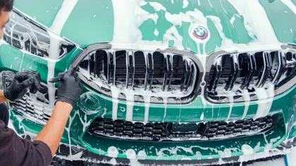 Close-up of a green BMW car front grille covered in soapy foam during a wash.