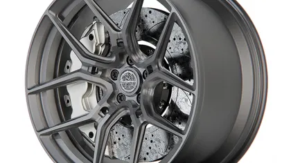Matte gray alloy wheel with intricate multi-spoke design and visible drilled brake rotor behind spokes.