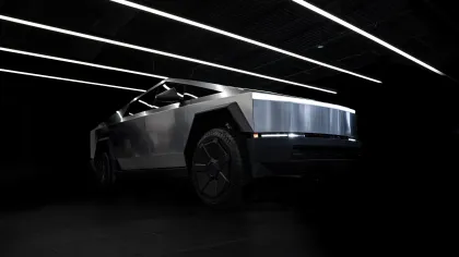 Sleek silver futuristic electric truck with sharp angular design showcased in dark room with neon ceiling lights