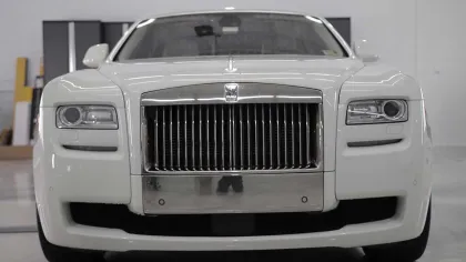 Front view of a white luxury Rolls-Royce car with signature chrome grille and sleek headlights.