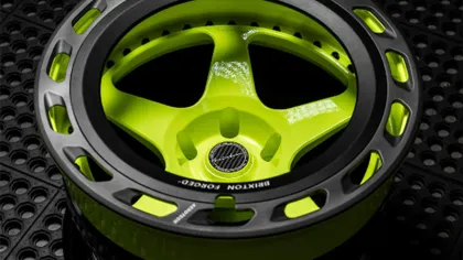 Glossy lime green and black Brixton Forged car wheel rim on textured black surface with modern design.