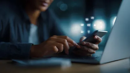 Person using smartphone with digital icons showing messages, email, and notifications over laptop keyboard.