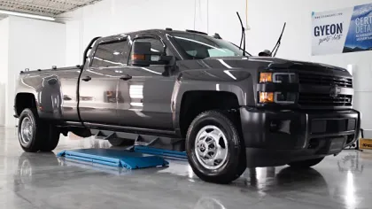 Dark gray heavy-duty pickup truck parked indoors on a blue vehicle lift in a clean garage.