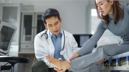 Doctor examining patient’s foot in a medical office focused on foot pain or injury diagnosis.