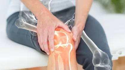 Person holding painful knee with digital overlay of knee joint bones highlighting inflammation or injury.
