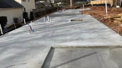 New concrete foundation slab with plumbing pipes set for residential home construction.