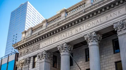Facade of United States National Bank building with classical columns and modern skyscraper in background.