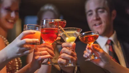 Group of friends clinking glasses with colorful cocktails and drinks at a party celebration.