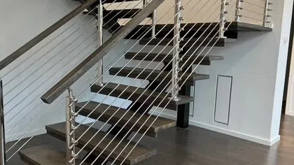 Modern floating staircase with dark wood steps and stainless steel cable railing in a contemporary interior
