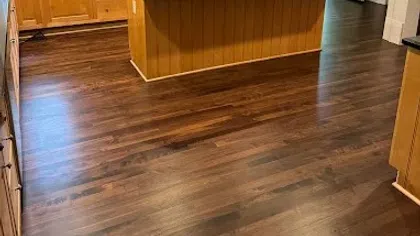 Spacious kitchen with wooden cabinets, dark granite countertops, a central island, and hardwood flooring.