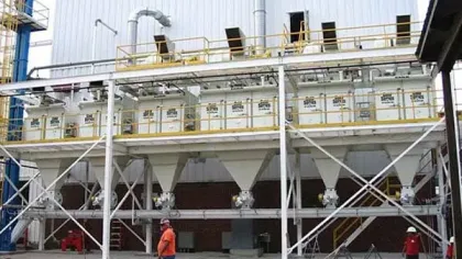 Industrial facility with large white storage silos and workers wearing safety gear operating machinery.
