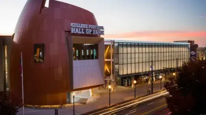 College Football Hall of Fame building illuminated at dusk with modern architecture and street lighting.