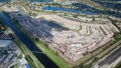 Aerial view of a large residential construction site with waterways, roads, and surrounding neighborhoods.