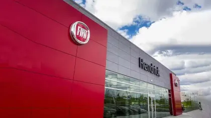 Fiat dealership building with red and gray panels under a partly cloudy sky