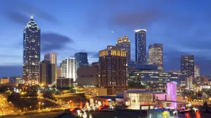 Nighttime view of a city skyline with illuminated skyscrapers and colorful lights along the streets.